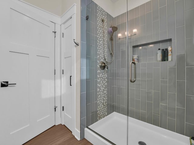 full bathroom featuring wood finished floors and a shower stall