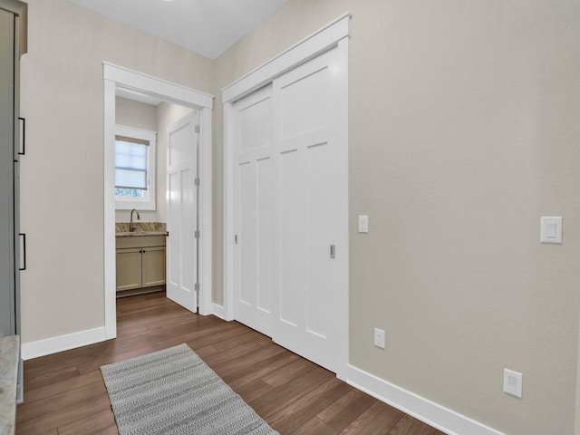 interior space with a sink, baseboards, and dark wood finished floors