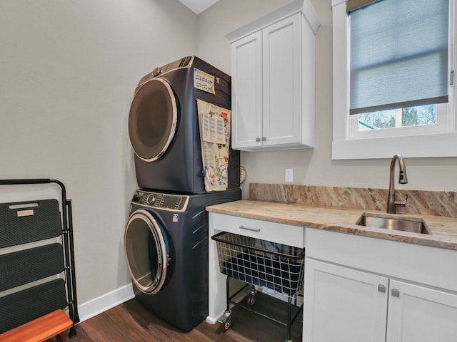 laundry area with baseboards, stacked washing maching and dryer, dark wood finished floors, cabinet space, and a sink