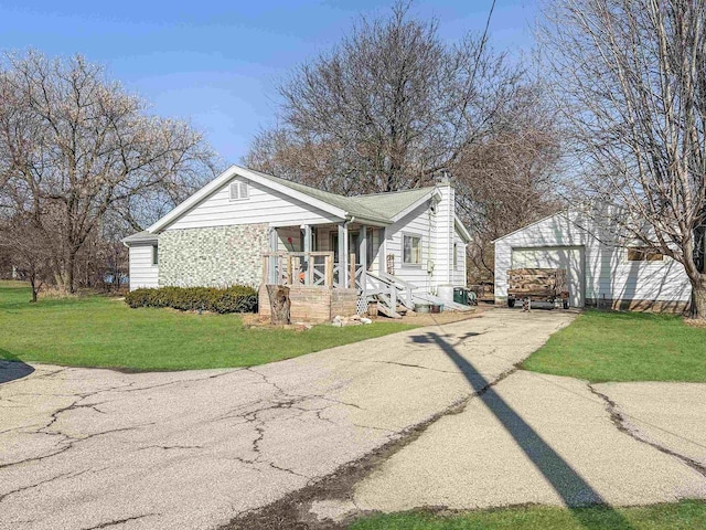 view of front of home featuring a front lawn, a porch, concrete driveway, a chimney, and an outbuilding