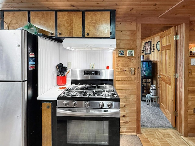 kitchen with appliances with stainless steel finishes, wood walls, and under cabinet range hood