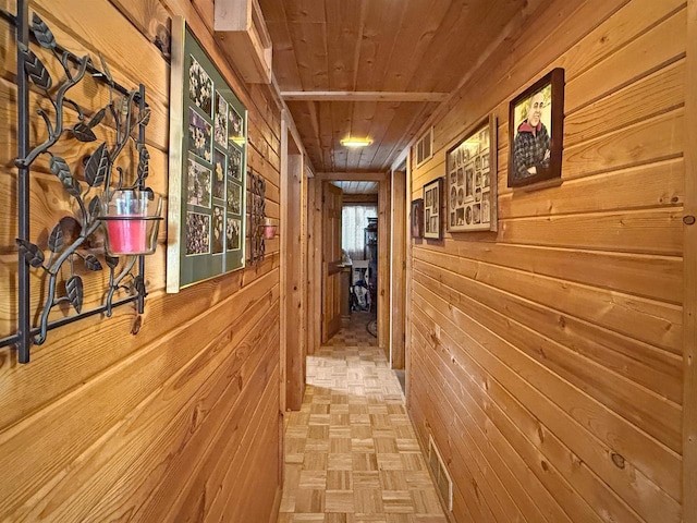 hallway featuring visible vents, wood ceiling, and wood walls