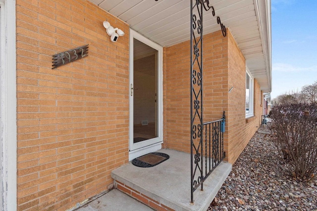 view of exterior entry with brick siding and covered porch