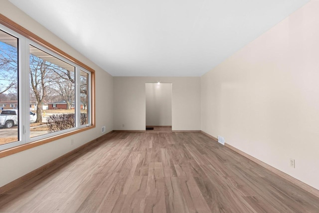 spare room with light wood finished floors, visible vents, and baseboards