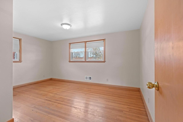 spare room featuring visible vents, light wood-type flooring, and baseboards