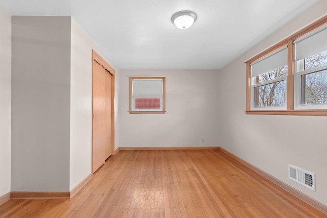 spare room featuring visible vents, baseboards, and light wood finished floors