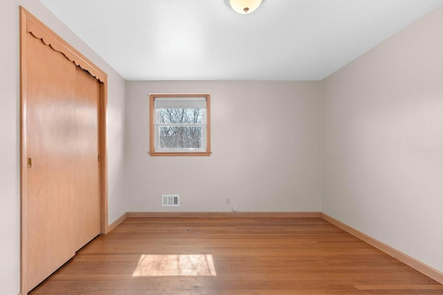 unfurnished bedroom with visible vents, baseboards, a closet, and light wood finished floors