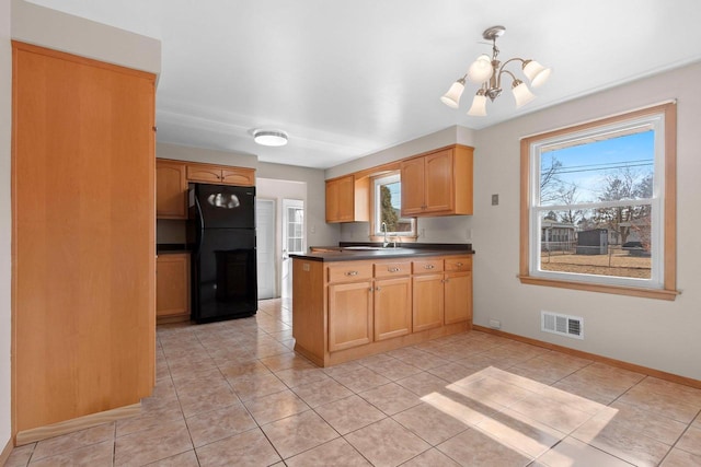 kitchen with visible vents, dark countertops, freestanding refrigerator, a peninsula, and a chandelier