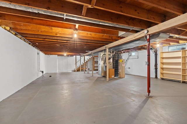 unfinished below grade area featuring stairway, heating unit, and water heater