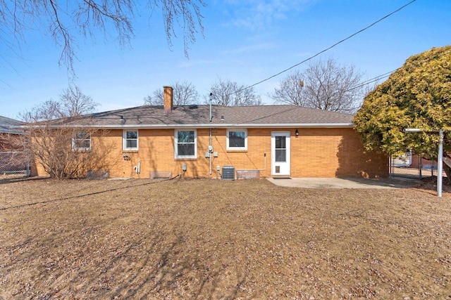 back of house with fence, cooling unit, a shingled roof, brick siding, and a patio area