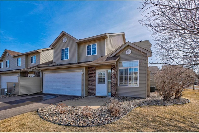 view of front of home featuring brick siding, cooling unit, driveway, and a garage