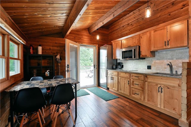 kitchen with a sink, stainless steel microwave, plenty of natural light, vaulted ceiling with beams, and dark wood-style flooring