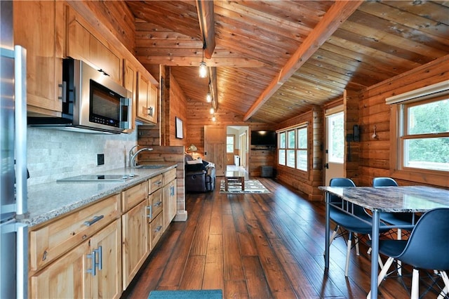 kitchen with wooden walls, dark wood finished floors, lofted ceiling with beams, wood ceiling, and stainless steel microwave