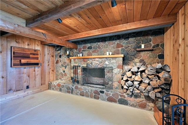 unfurnished living room featuring beam ceiling, wooden walls, wooden ceiling, and a stone fireplace