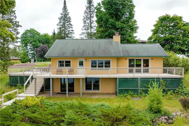 back of property featuring a chimney, a deck, and stairs