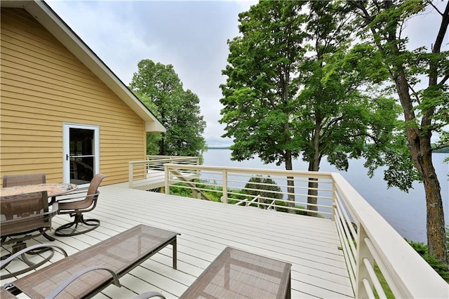 wooden deck with a water view and outdoor dining space