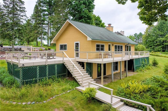 back of house featuring a wooden deck, stairway, and a chimney