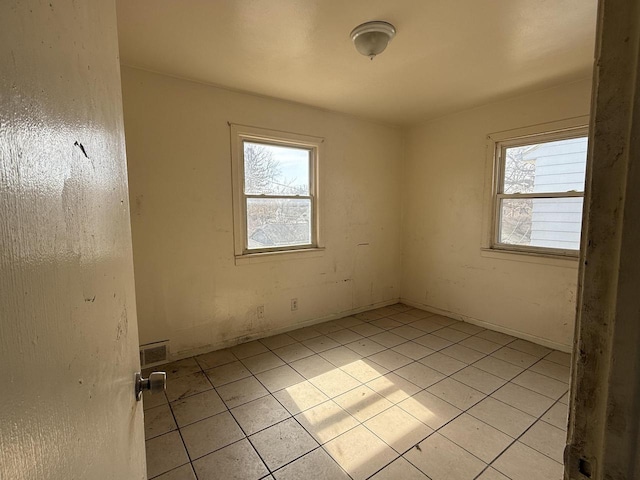 spare room with a wealth of natural light, light tile patterned floors, and visible vents