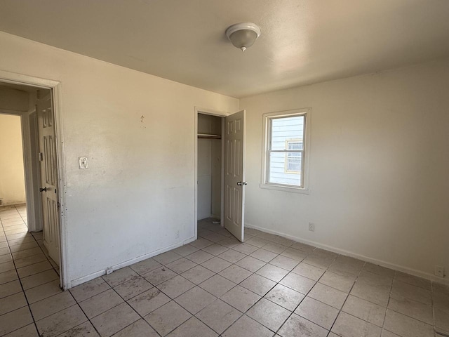 unfurnished bedroom featuring a closet, baseboards, and light tile patterned flooring