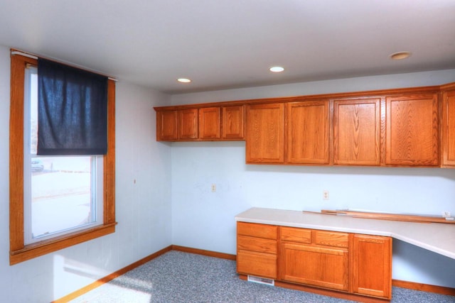 kitchen with light countertops, recessed lighting, brown cabinetry, and baseboards