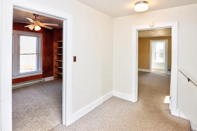 hallway featuring a baseboard heating unit, carpet flooring, and baseboards