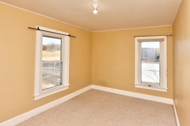 carpeted empty room with a healthy amount of sunlight and baseboards