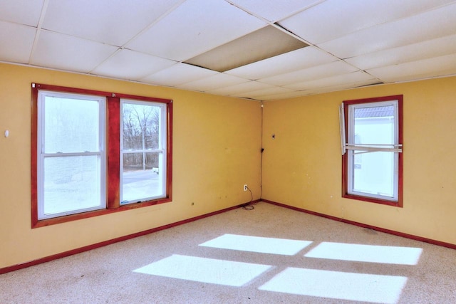 carpeted spare room with a drop ceiling and baseboards