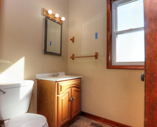 bathroom with toilet, vanity, and baseboards