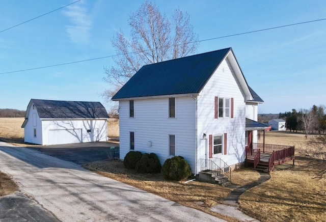 view of side of property with an outbuilding, a garage, and metal roof