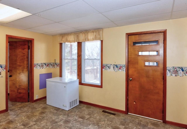 foyer entrance featuring baseboards and a paneled ceiling