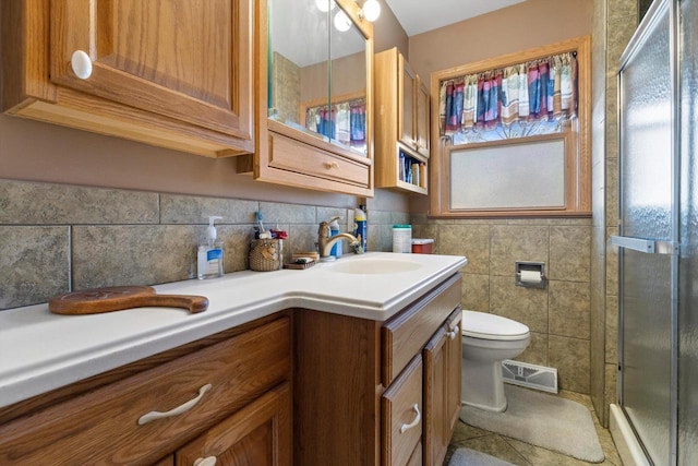 full bath featuring visible vents, double vanity, a sink, a shower stall, and toilet