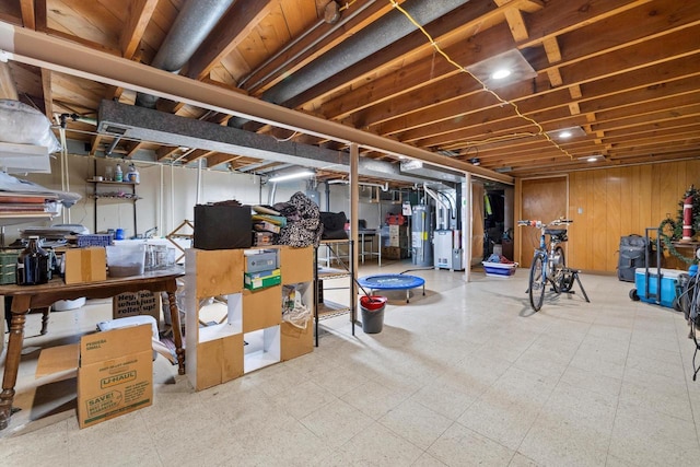 unfinished below grade area featuring tile patterned floors, wooden walls, and gas water heater