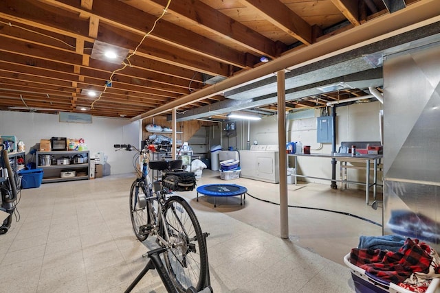 unfinished below grade area with tile patterned floors, electric panel, and washing machine and clothes dryer