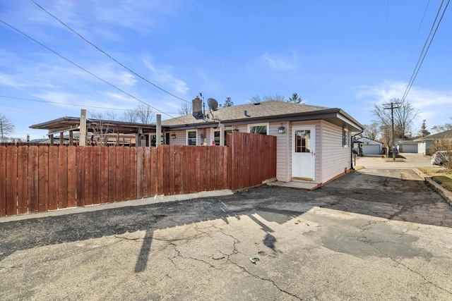 exterior space featuring an outbuilding, a chimney, and fence