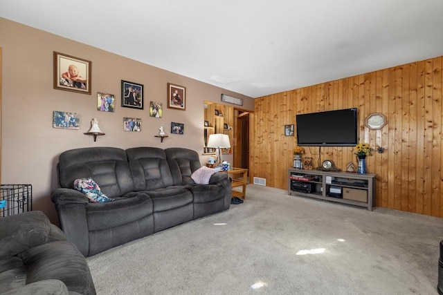 carpeted living room featuring visible vents and wood walls