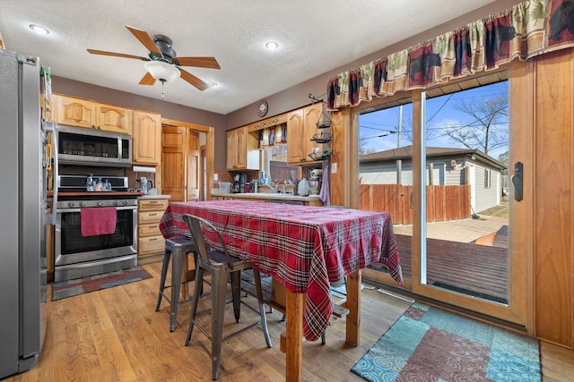 dining space with light wood finished floors, a textured ceiling, and a ceiling fan