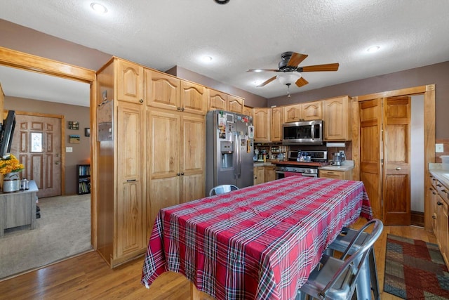 kitchen with ceiling fan, light countertops, light wood-style floors, appliances with stainless steel finishes, and a textured ceiling