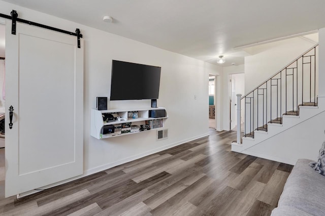 living room with visible vents, baseboards, stairs, a barn door, and wood finished floors