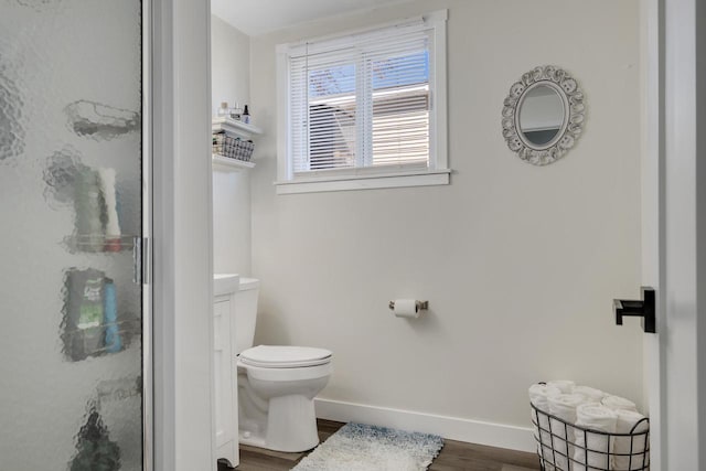 bathroom with a shower stall, toilet, wood finished floors, and baseboards