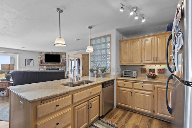 kitchen featuring light stone counters, a peninsula, dark wood-style floors, stainless steel appliances, and a sink