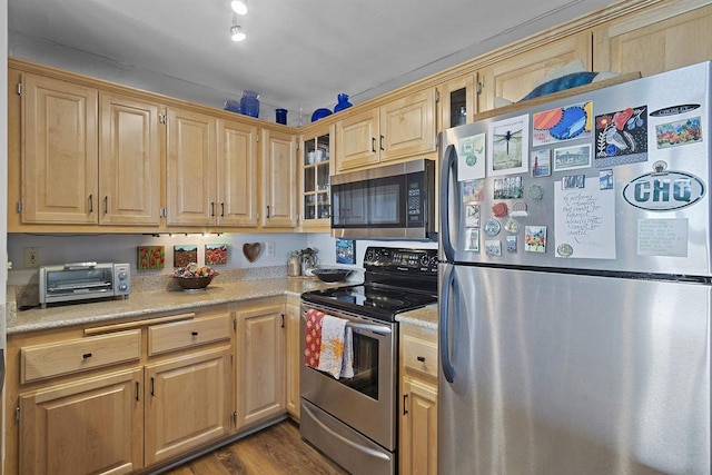 kitchen featuring light countertops, a toaster, appliances with stainless steel finishes, and light brown cabinetry