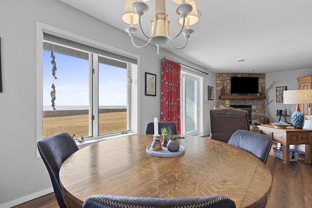 dining space featuring a notable chandelier, a fireplace, dark wood-type flooring, and baseboards