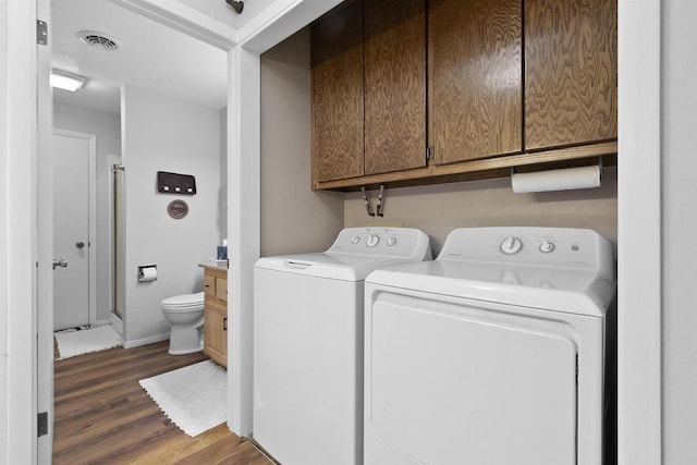 washroom featuring wood finished floors, visible vents, baseboards, cabinet space, and separate washer and dryer