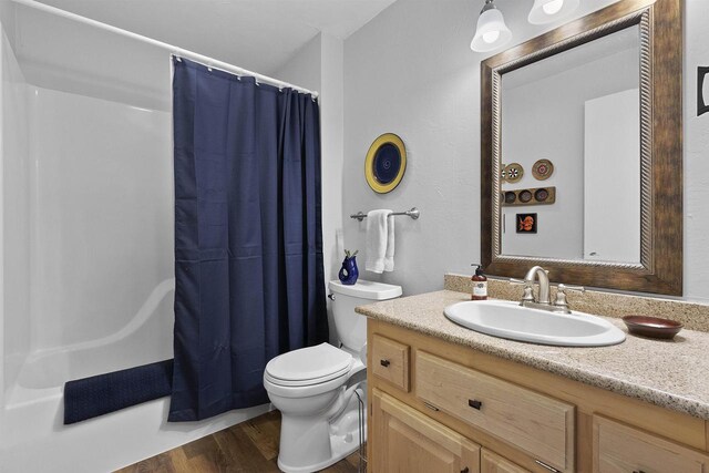 bathroom featuring toilet, wood finished floors, vanity, and shower / bath combination with curtain