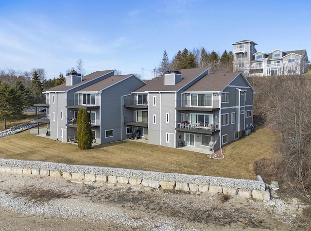 back of property with a residential view, a chimney, and a yard