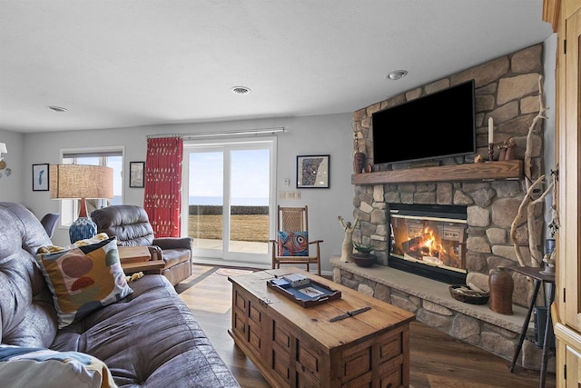 living area featuring visible vents, a stone fireplace, and wood finished floors