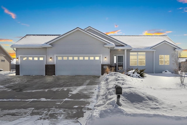 ranch-style home featuring an attached garage, brick siding, and driveway