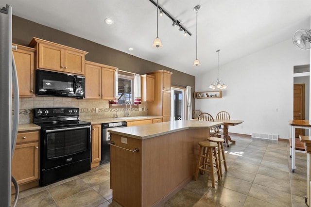 kitchen with a kitchen island, black appliances, light countertops, vaulted ceiling, and backsplash