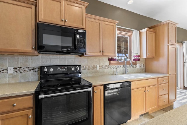 kitchen featuring a sink, decorative backsplash, black appliances, and light countertops