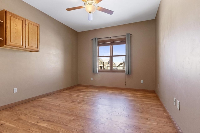 spare room with baseboards, light wood-type flooring, and ceiling fan